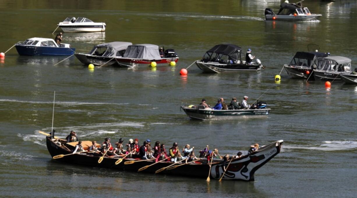 File - In this May 4, 2011 file photo, a group of people in a large canoe head upriver into scores of fishing boats during the Spring Chinook Salmon run on the Willamette River in Oregon City, Ore. Federal officials are considering putting a once-flourishing West Coast salmon on the list of threatened or endangered species. The National Marine Fisheries Services said Tuesday, Feb. 27, 2018, it will investigate whether to give protected status to spring-run Chinook salmon in and around the Klamath River.