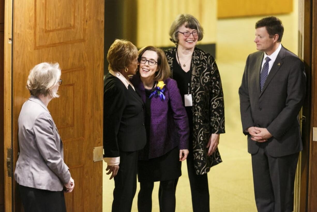 Gov. Kate Brown, center, greets Sen. Jackie Winters, D-Salem, before the State of the State address Monday at the Oregon State Capitol in Salem, Ore. Molly J.