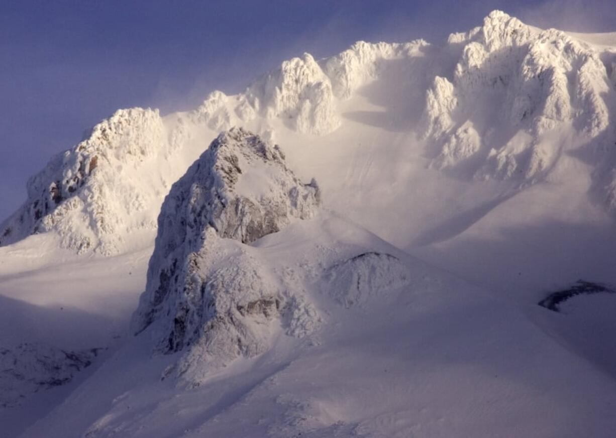 High winds whip snow off the western peaks of Mount Hood as seen from Government Camp, Ore. Rescuers scrambled to Oregon’s tallest peak Tuesday after a climber fell several hundred feet and seven others were stranded.