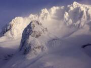 High winds whip snow off the western peaks of Mount Hood as seen from Government Camp, Ore. Rescuers scrambled to Oregon’s tallest peak Tuesday after a climber fell several hundred feet and seven others were stranded.