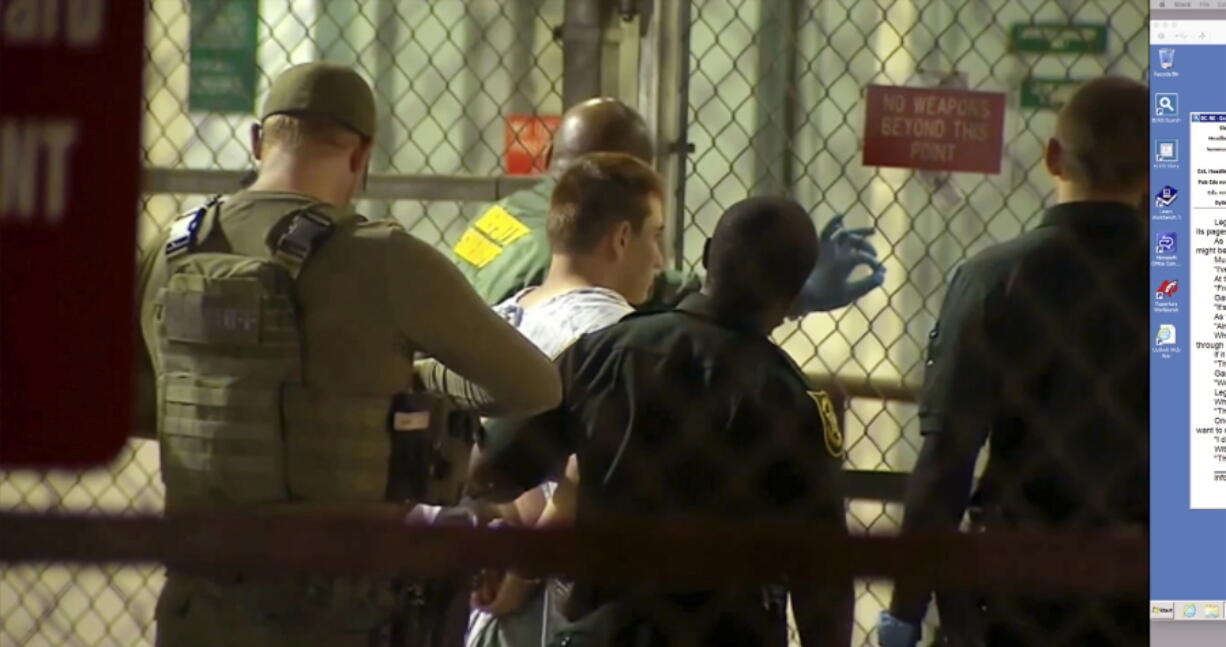 In this frame grab from video provided by WPLG-TV, police take Nikolas Cruz into Broward County jail on Thursday in Fort Lauderdale, Fla. Cruz was charged with 17 counts of premeditated murder Thursday morning after being questioned for hours by state and federal authorities.