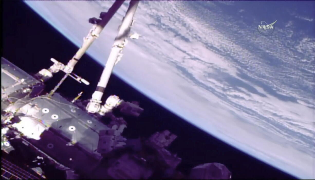 Astronauts Norishige Kanai of Japan, left, and NASA astronaut Mark Vande Hei work on the International Space Station’s robot arm during a spacewalk Friday.