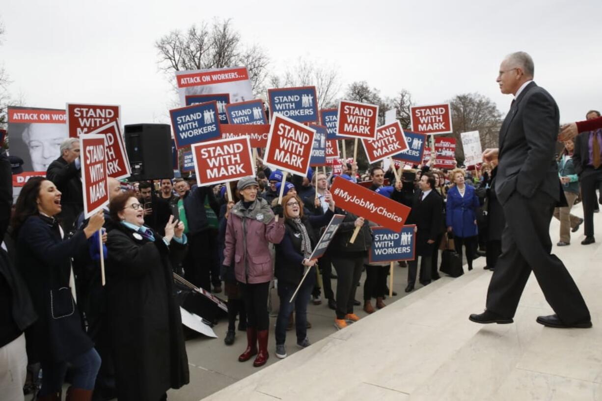 Supporters of Illinois government employee Mark Janus cheer as he walks to thank them Monday outside the Supreme Court in Washington. The court is considering a challenge to an Illinois law that allows unions to collect fees.