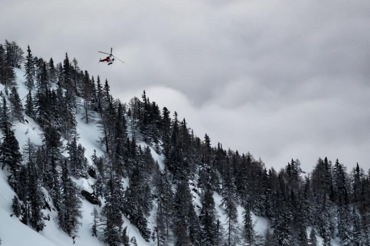 A helicopter leaves from the location where an avalanche left two people injured, at the Fenestral Pass, in Finhaut, Switzerland, Sunday, Feb. 18, 2018. Valais police spokesman Stefan Leger said Sunday that two people were hospitalized after being pulled from the snow.