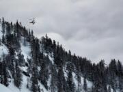 A helicopter leaves from the location where an avalanche left two people injured, at the Fenestral Pass, in Finhaut, Switzerland, Sunday, Feb. 18, 2018. Valais police spokesman Stefan Leger said Sunday that two people were hospitalized after being pulled from the snow.