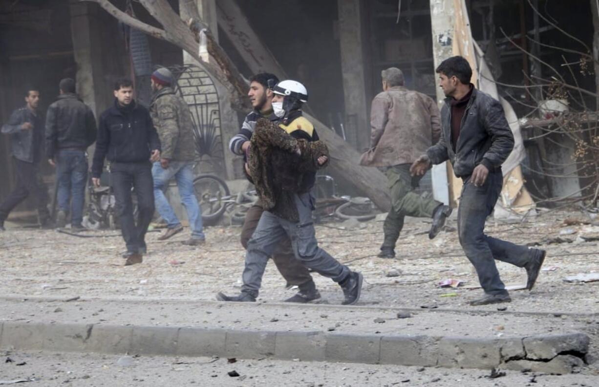 A civil defense worker carries a victim after airstrikes hit a rebel-held suburb near Damascus, Syria, Thursday. Syrian rescue workers and activists say the death toll from ongoing government strikes on the opposition-held region near the capital Damascus has risen to at least 35.