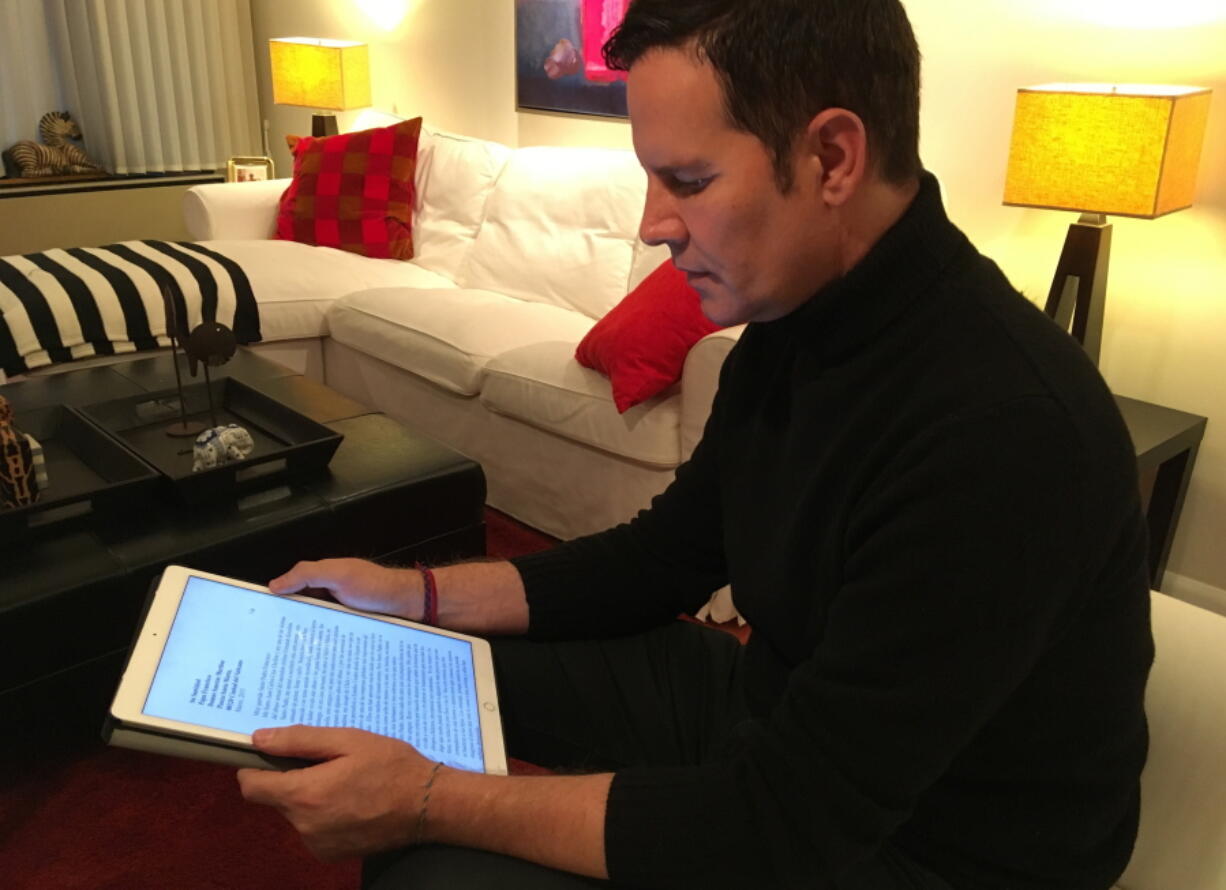 Juan Carlos Cruz reads from his tablet during an interview with The Associated Press in Philadelphia on Sunday. Cruz says Pope Francis received a letter he wrote in 2015 detailing the sexual abuse he suffered at the hands of a priest and efforts by the Chilean church to cover it up, contradicting the pope’s recent insistence that no victims had come forward.