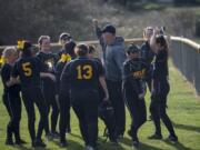 The Hudson’s Bay softball team gathers around coach Tony Christiansen in between innings in a game against Washougal on March 12. Hudson’s Bay is hoping success in fall slowpitch carries over to this spring.