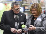 Ridgefield Mayor Ron Onslow looks at a bottle of Vitafusion chewable vitamins with Church & Dwight Co. Inc. Vice President of Sales Lisa MacMillin on Dec. 14, at an event in Vancouver. Onslow is stepping down as mayor after 10 years in office.