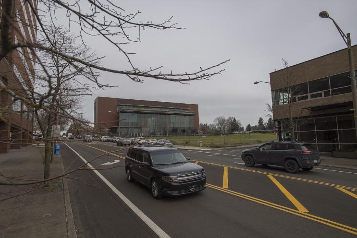 Motorists traveling on C Street navigate past parked cars surrounding the fenced-off site of a future elementary school Wednesday morning in downtown Vancouver. The school is one of several projects, completed and coming, that’s driving the city to re-examine parking around downtown.