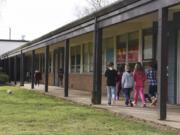 Students at Glenwood Heights Primary School walk down a covered walkway to a classroom Wednesday. The school, which was built in 1956, has many outdoor classroom entrances, which Battle Ground Public Schools says poses a safety concern. The district is seeking approval of a $224.9 million bond issue in an April 24 special election.