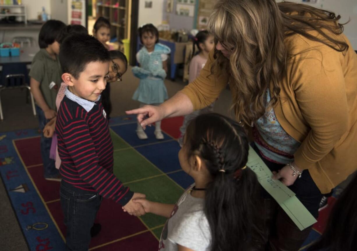 Mateo Gonzalez, 4, from left, and Aline Nieto, 5, learn from Julie Mills how to introduce themselves during an evening preschool session at Sarah J. Anderson Elementary School in Vancouver on Monday. The district offers free preschool classes at some campuses to help prepare students for kindergarten.