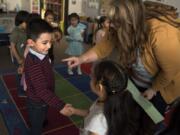 Mateo Gonzalez, 4, from left, and Aline Nieto, 5, learn from Julie Mills how to introduce themselves during an evening preschool session at Sarah J. Anderson Elementary School in Vancouver on Monday. The district offers free preschool classes at some campuses to help prepare students for kindergarten.