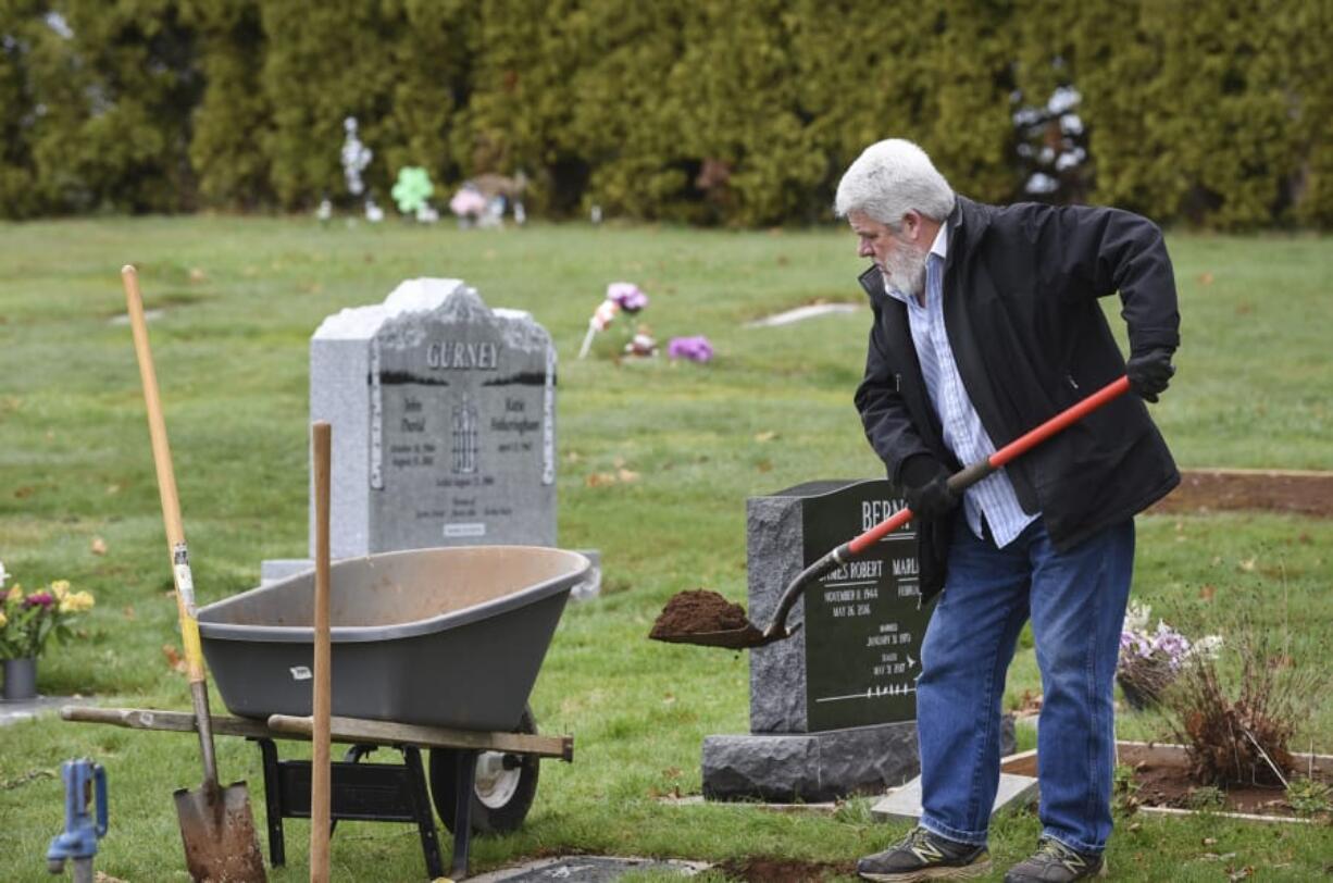 John Straub, commissioner and groundskeeper at Fern Prairie Cemetery in Camas, digs a hole for an urn of someone he once knew in the community.