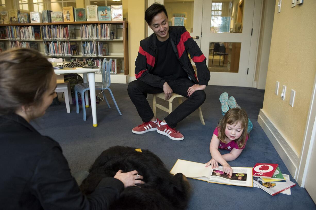 Camas High School seniors Kaylee Merritt, far left, and Aaron Le listen to Lisa Wooten of Camas, 4, as she reads to Cooper on Tuesday at the Camas Public Library. Merritt and Le rotate with two other students on Tuesdays and Thursdays, working with Cooper for their high school senior projects.