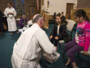 Caylin Orozco, 6, center, and Darisley Gonzales, 8, right, both of Vancouver, take a seat as the Rev. Dennis Cole, assistant rector, washes their feet during the Maundy Thursday service at St. Luke’s Episcopal Church. Foot washing is a hallmark of the holy day commemorating the Last Supper.