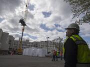 Bobby Blanks, safety manager for Howard S. Wright Construction, looks on as a crane lifts a Kia Soul over a building at PeaceHealth Southwest Medical Center. The vehicle, donated by Dick Hannah Kia, was placed on a third-floor outdoor patio and will be used by rehabilitation patients learning how to enter and exit a vehicle.