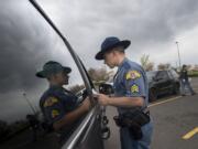 Sgt. Jason Cuthbert of the Washington State Patrol is reflected in the window of a car as he issues an infraction for distracted driving in southeast Vancouver in April.