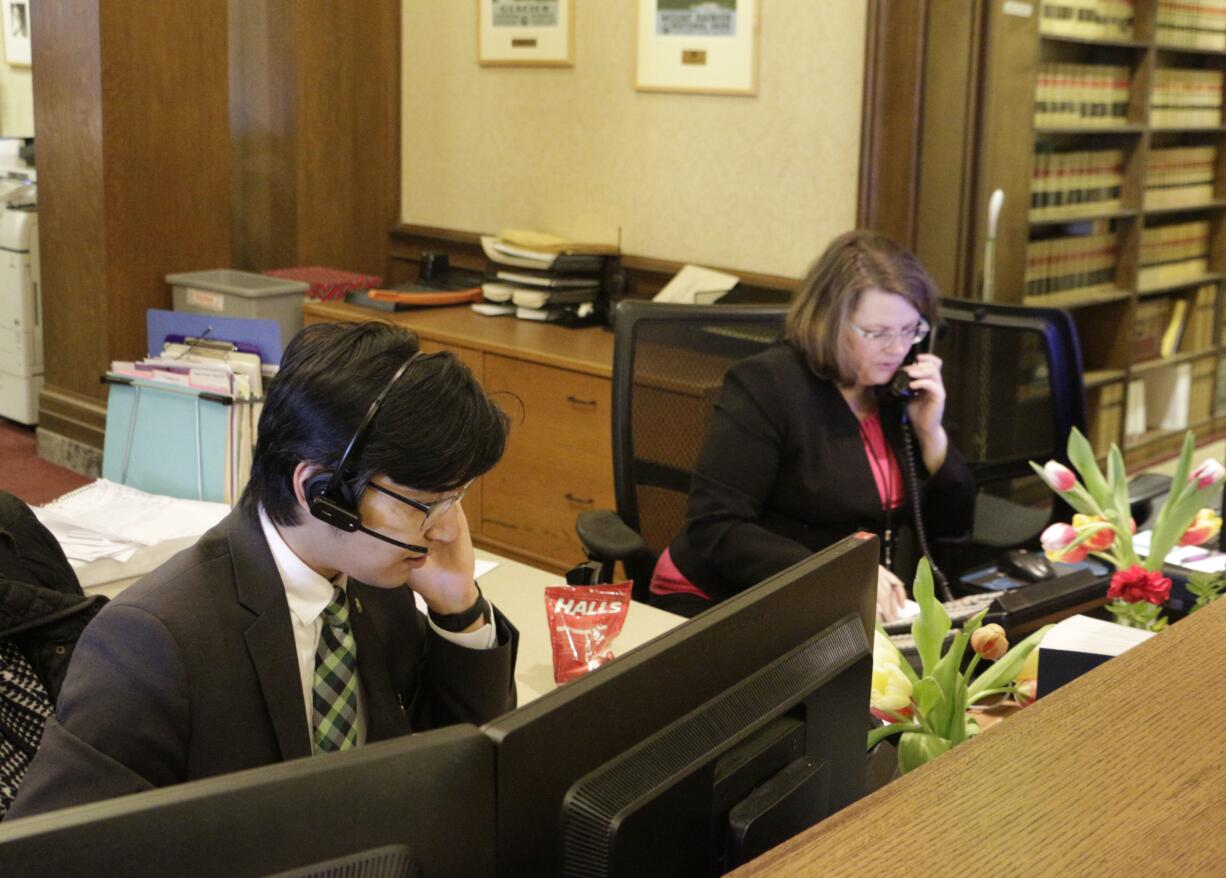 Kento Azegami, left, and Jeanne Blackburn answer phones at the front desk at Gov. Jay Inslee's office in Olympia, Wash., on Thursday, March 1, 2018. Inslee's office has been receiving thousands of emails and phone calls asking him to veto a bill passed hastily by the Washington Legislature last week that would circumvent a recent court ruling that found state lawmakers are fully subject to the state's Public Records Act.