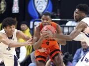 Washington's Matisse Thybulle, left, and Jaylen Nowell, right, and Oregon State's Alfred Hollins reach for a loose ball during the first half of an NCAA college basketball game in the first round of the Pac-12 men's tournament Wednesday, March 7, 2018, in Las Vegas.