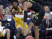 Southern California's Jonah Mathews, left, passes the ball around Oregon's Kenny Wooten during the first half of an NCAA college basketball game in the semifinals of the Pac-12 men's tournament Friday, March 9, 2018, in Las Vegas.