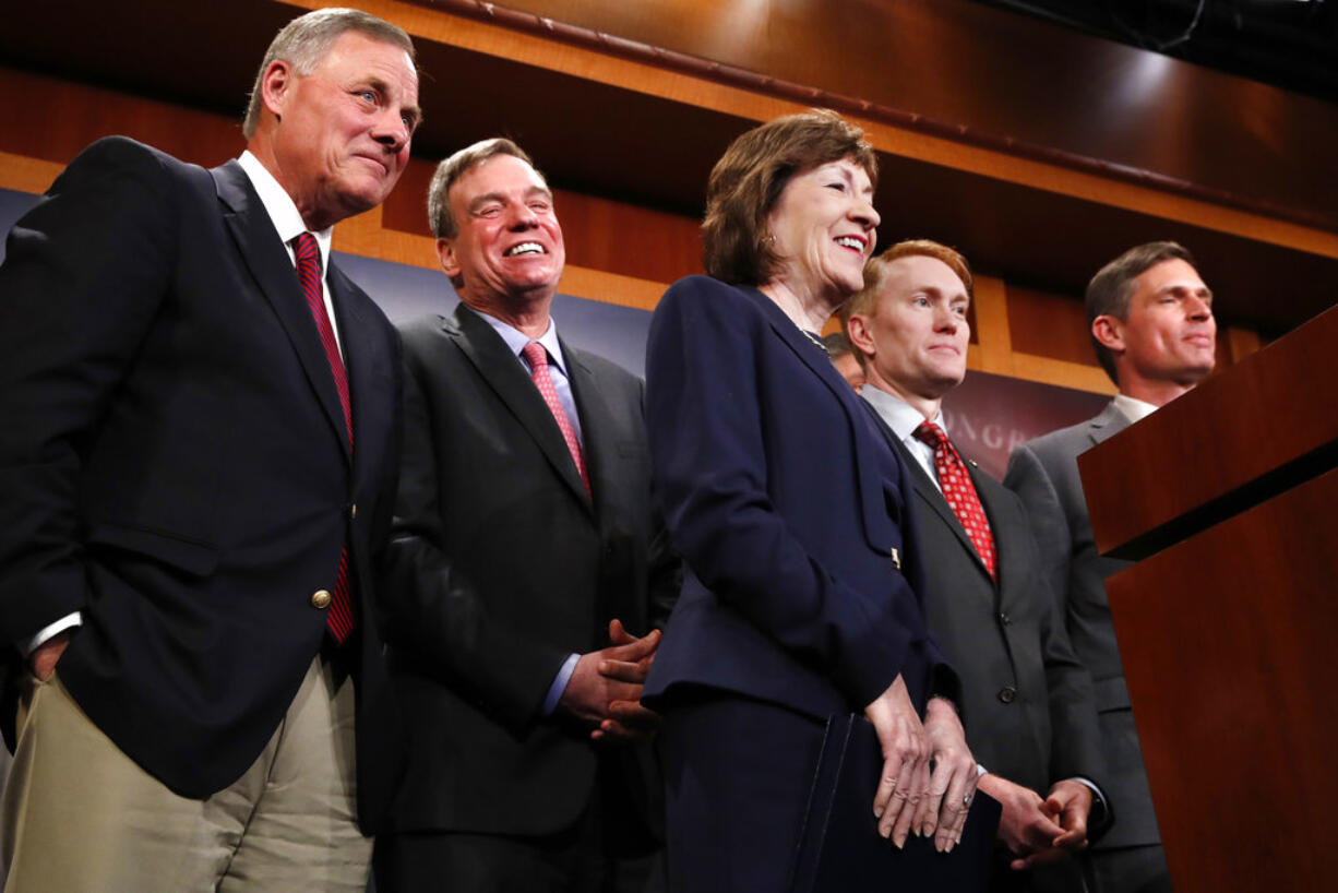 Members of the Senate Intelligence Committee, including Chairman Sen. Richard Burr, R-N.C., left, Vice Chair Sen. Mark Warner, D-Va., Sen. Susan Collins, R-Maine, Sen. James Lankford, R-Okla., and Sen. Martin Heinrich, D-N.M., react as the group declines to answer a question about President Donald Trump, Tuesday, March 20, 2018, on Capitol Hill in Washington.