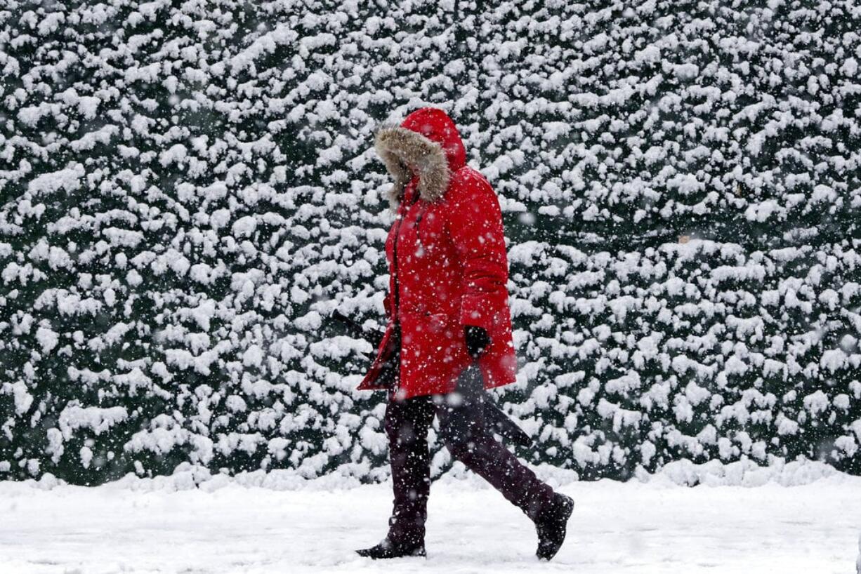 A woman approaches the Hoboken Terminal of the PATH train system as light snow falls Wednesday, March 21, 2018, in Hoboken, N.J. A spring nor'easter targeted the Northeast on Wednesday with strong winds and a foot or more of snow expected in some parts of the region.