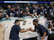 Villanova's Jalen Brunson, left, and Phil Booth, right, celebrate with teammates after affixing the team name on the bracket after beating Texas Tech in an NCAA men's college basketball tournament regional final, Sunday, March 25, 2018, in Boston. Villanova won 71-59 to advance to the Final Four.