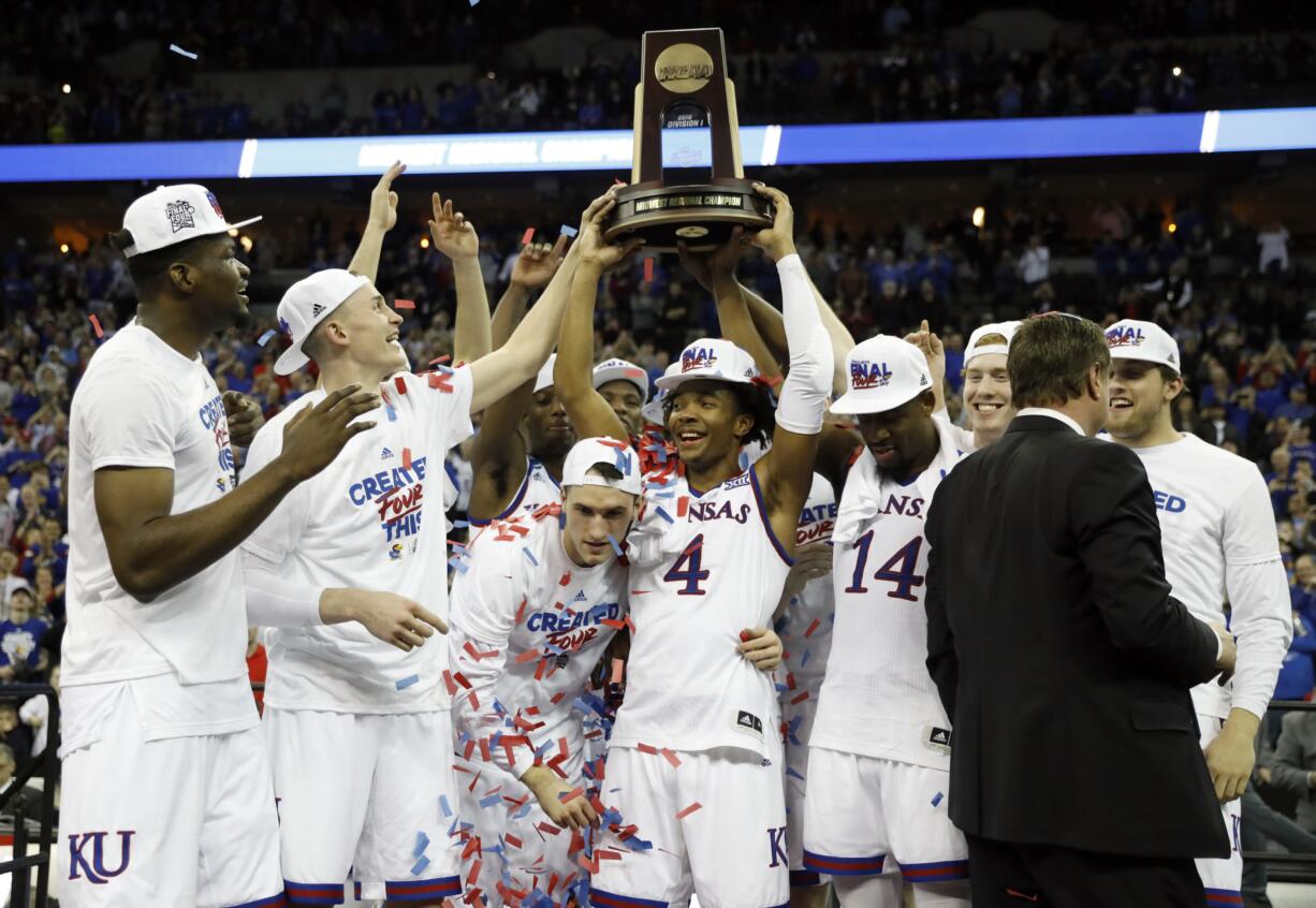 Kansas' Devonte' Graham (4) holds the trophy after defeating Duke in a regional final game in the NCAA men's college basketball tournament Sunday, March 25, 2018, in Omaha, Neb. Kansas won 85-81 in overtime.