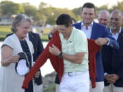 Rory McIlroy, of Northern Ireland, gets help putting on the championship sweater by Arnold Palmer’s grandson, Sam Saunders, right, and his widow, Kit Palmer, left, after winning the Arnold Palmer Invitational golf tournament Sunday, March 18, 2018, in Orlando, Fla. (AP Photo/Phelan M.