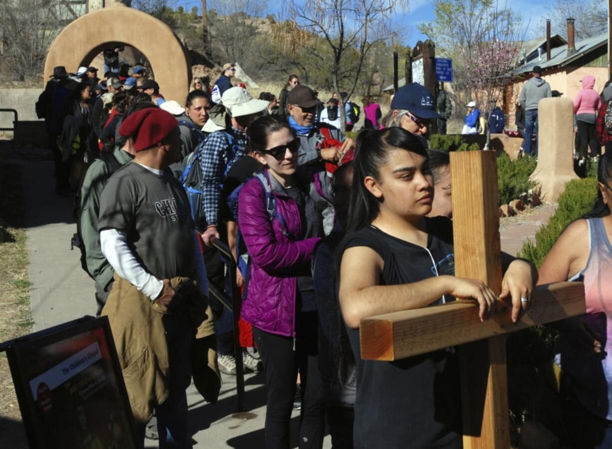 Jasmin Perez, 17, of Espanola, New Mexico, carries a cross on a pilgrimage to a small adobe church in Chimayo, New Mexico, on Friday, March 30, 2018. She joined thousands of Catholics traveled by foot to El Santuario de Chimayo in the hills of northern New Mexico in an annual Good Friday pilgrimage that has endured for two centuries. The Easter-week tradition attracts more than 20,000 people. Many set out before dawn and walk more than 30 miles (48 kilometers) along highways from Santa Fe.