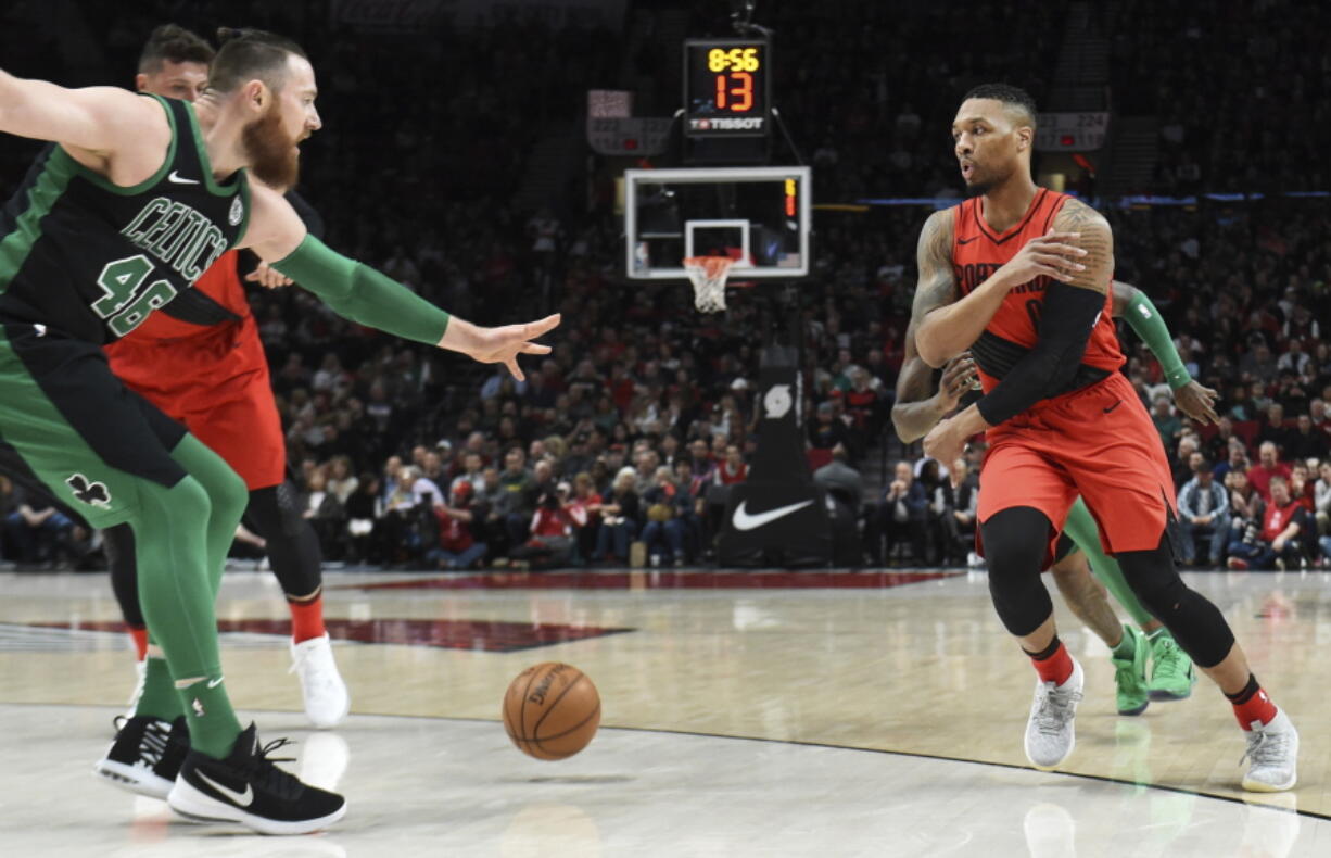 Portland Trail Blazers guard Damian Lillard passes the ball on Boston Celtics center Aron Baynes during the first half of an NBA basketball game in Portland, Ore., Friday, March 23, 2018.