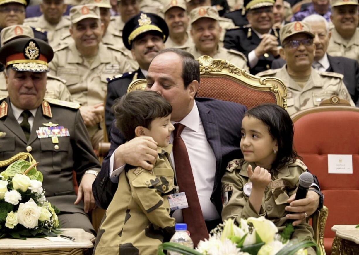 In this photo released by the Egyptian Presidency, Egyptian President Abdel-Fattah el-Sissi, center, kisses the forehead of a child of a fallen soldier during a conference commemorating the country’s martyrs, in Cairo, Egypt, Thursday, March 15, 2018. Up for re-election in less than two weeks, Egypt’s president on Thursday took center stage at a televised ceremony declaring his readiness to personally join the battle against militants and decorating soldiers and families of fallen ones.