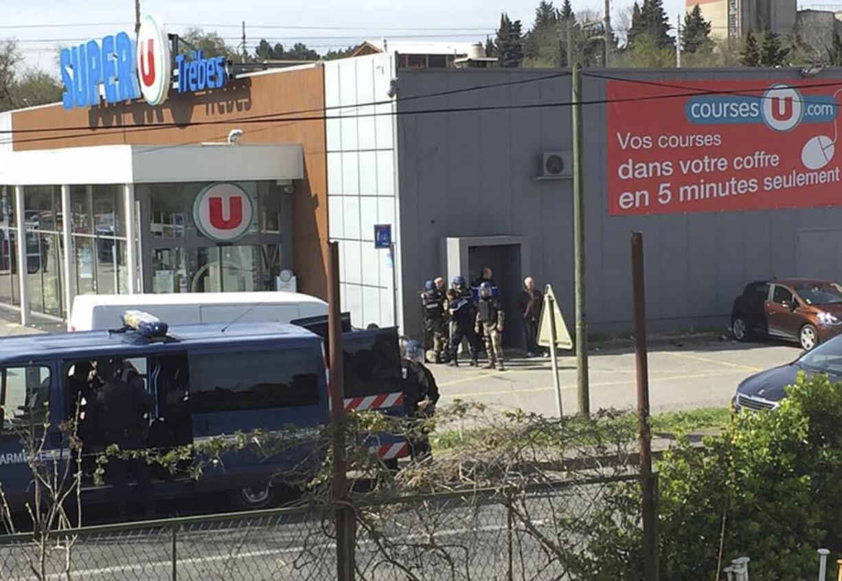 Police gather Friday outside a supermarket in Trebes, southern France, where an armed man took hostages.