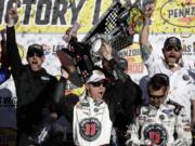 Kevin Harvick hoists the trophy with his team after winning a NASCAR Cup series auto race Sunday, March 4, 2018, in Las Vegas.