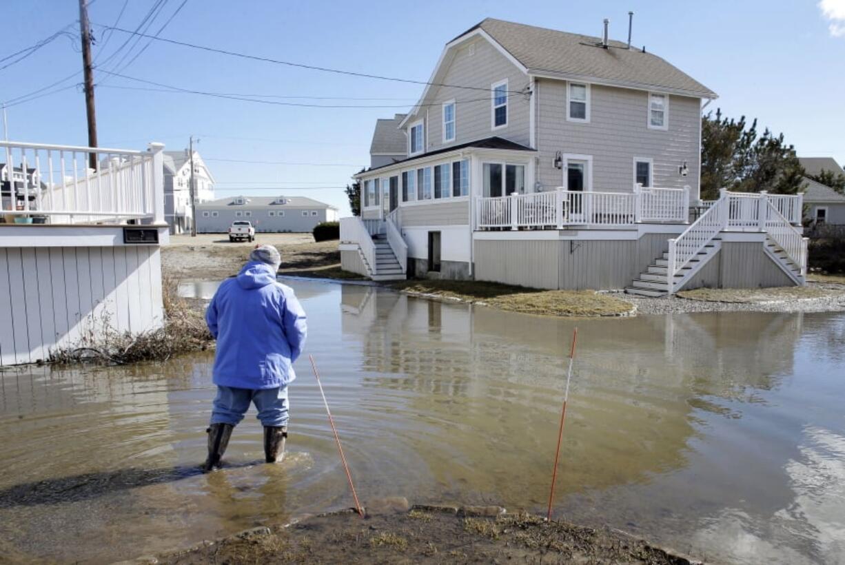 A resident of Duxbury, Mass., views flooding near her home, Sunday, March 11, 2018, in Duxbury. The Northeast is bracing for its third nor’easter in fewer than two weeks. The National Weather Service reports Sunday that a southern storm is expected to make its way up the coast causing more snowfall.