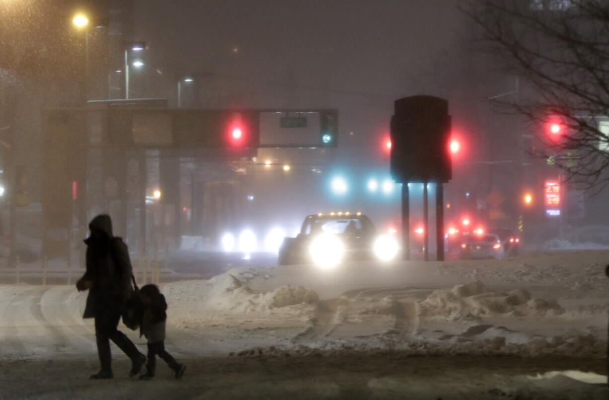 A woman and a child cross a snow-covered street during a snowstorm, Wednesday, March 21, 2018, in Jersey City, N.J. A spring nor’easter targeted the Northeast on Wednesday with strong winds and a foot or more of snow expected in some parts of the region.