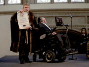 FILE - In this March 6, 2017 file photo, Britain’s Professor Stephen Hawking is presented with his illuminated Freedom scroll by the Chamberlain of the City of London Peter Kane as he receives the Honorary Freedom of the City of London during a ceremony at the Guildhall in the City of London. Hawking, whose brilliant mind ranged across time and space though his body was paralyzed by disease, has died, a family spokesman said early Wednesday, March 14, 2018.