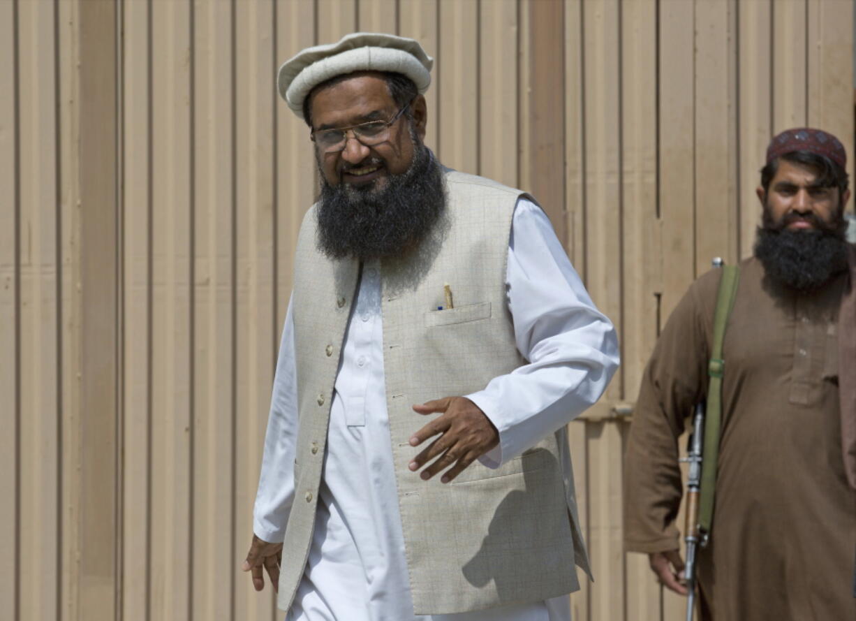 Pakistani militant leader Fazlur Rehman Khalil, left, arrives at his compound in Islamabad, Pakistan. In an exclusive interview with The Associated Press, Khalil, whose group Harakat-ul-Mujahedeen, now known as Ansar-ul Ummah, is on the US designated terrorist list, tells of a fatwa he helped craft outlawing violent militancy in Pakistan. Yet just his mere presence on the outskirts of the Pakistan capital has analysts questioning Pakistan’s readiness to rout militants and their followers from its territory. (AP Photo/B.K.