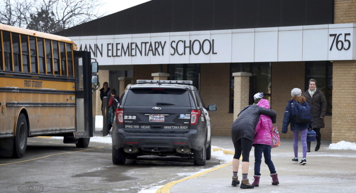 Meghan Stephenson hugs her child before staying goodbye Feb. 22, outside Orono Schumann Elementary School as a police officer stands nearby as students arrive for the day after a threat was posted, causing Orono, Minn., schools to go on lockdown.