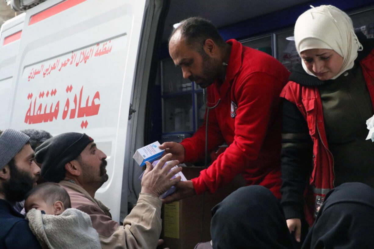 Members of the Syrian Red Crescent distributing medicines for civilians in Douma, eastern Ghouta, a suburb of Damascus, Syria, on Monday. Desperate for food and medicine, Syrian civilians in the war-ravaged eastern suburbs of Damascus hoped for relief Monday as a 46-truck aid convoy began entering the rebel stronghold, the first such shipment in months.