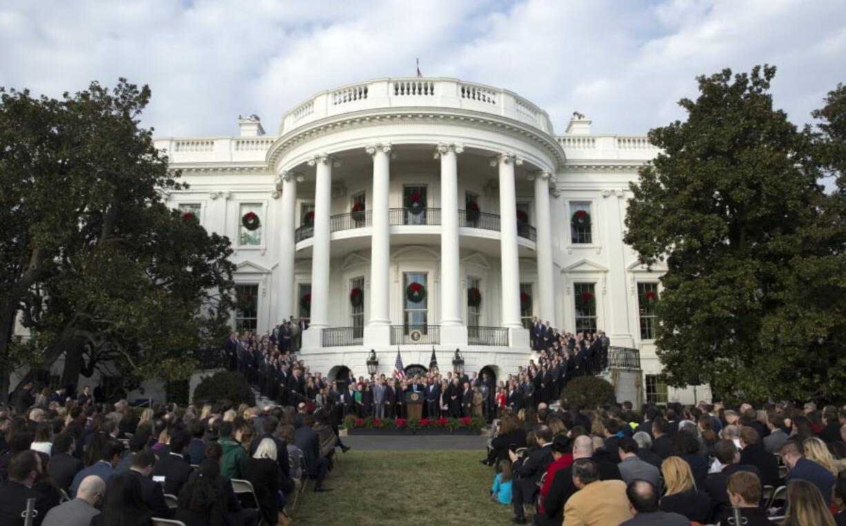 FILE - In this Dec. 20, 2017, file photo, President Donald Trump, surrounded by members of congress and supporters, speaks during an event on the South Lawn of the White House in Washington, to acknowledge the final passage of tax overhaul legislation by Congress. The new tax law ends a benefit long prized by business for schmoozing with customers or courting new ones. And the impact could be felt in big glitzy boxes at sports stadiums, or even at minor league games in small towns with loyal company backers.