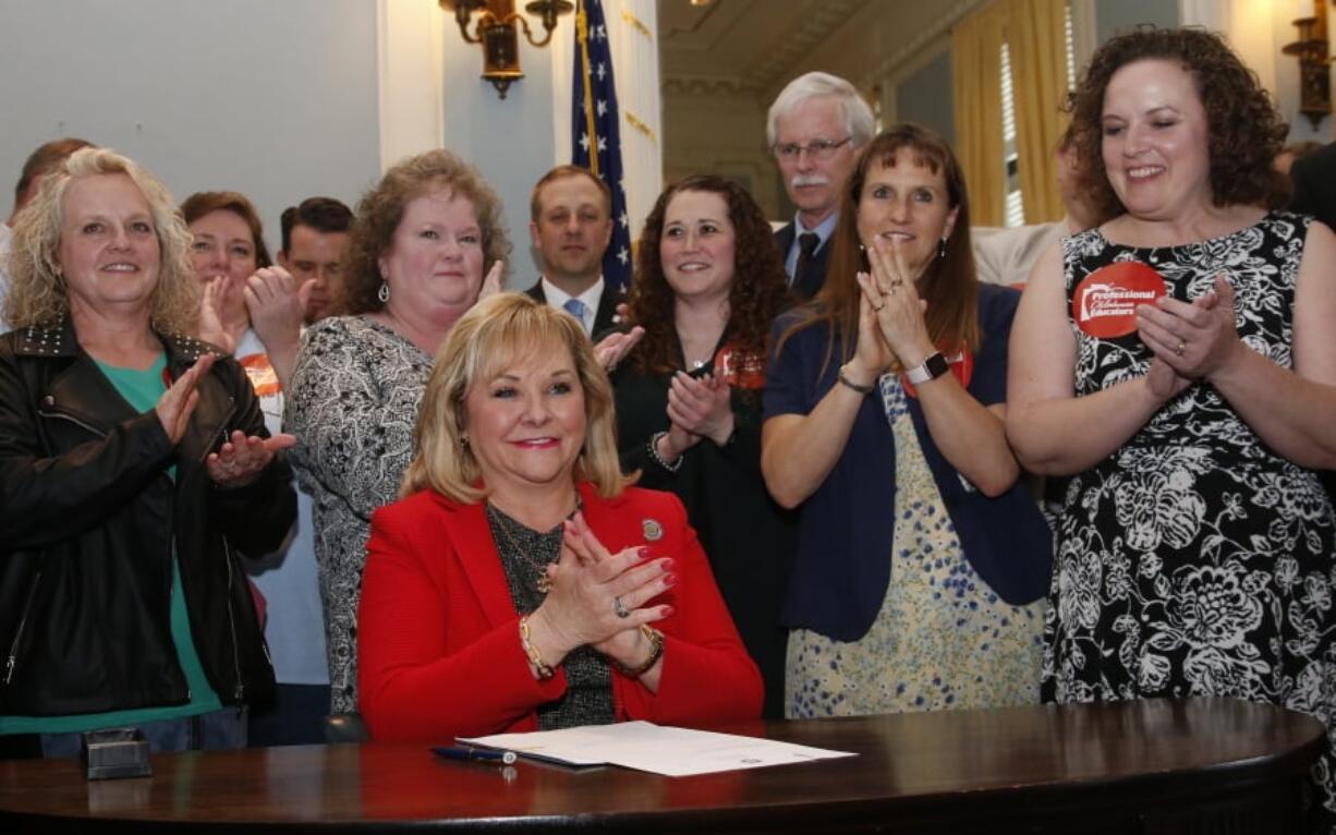 Surrounded by teachers and legislators, Oklahoma Gov. Mary Fallin applauds after signing a teacher pay raise bill in Oklahoma City, Thursday, March 29, 2018.