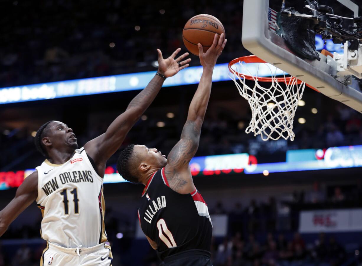 New Orleans Pelicans guard Jrue Holiday (11) blocks a shot by Portland Trail Blazers guard Damian Lillard (0) in the second half of an NBA basketball game in New Orleans, Tuesday, March 27, 2018. The Trail Blazers won 107-103.