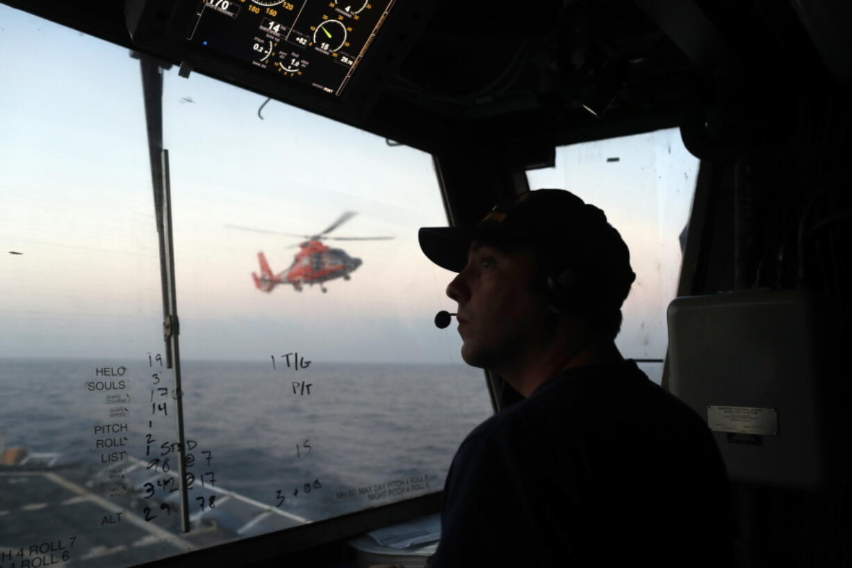 FILE - In this March 2, 2017 photo, an unidentified U.S. Coast Guardsman communicates with the pilot of a helicopter during take-off and landing exercises on the U.S. Coast Guard cutter Stratton in the eastern Pacific Ocean. The U.S. Coast Guard is teaming up with the Mexican and Colombian navies off South America’s Pacific coast to go after seafaring smugglers, opening a new front in the drug war.