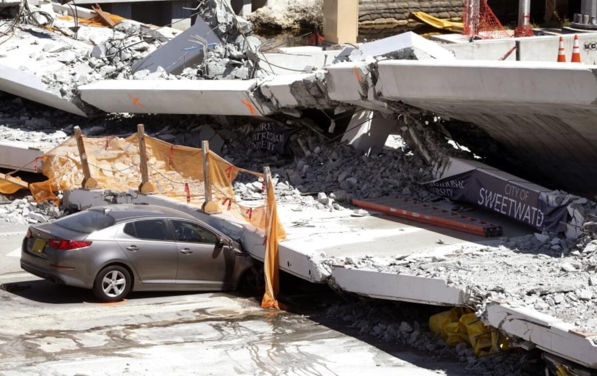 Crushed cars are shown under a section of a collapsed pedestrian bridge Friday near Florida International University in the Miami area. The bridge collapsed Thursday onto a busy highway, crushing vehicles beneath massive slabs of concrete and steel.