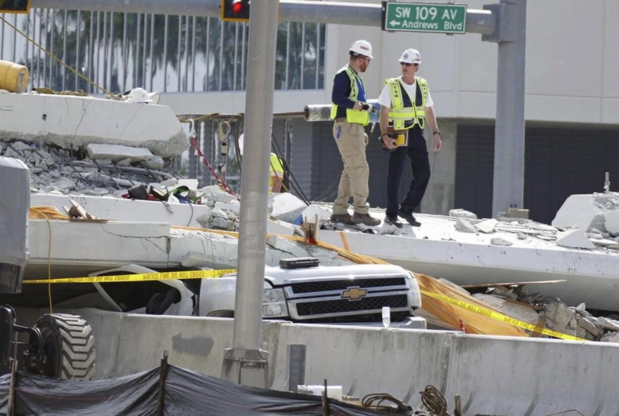 Inspectors walks over what remains of a pedestrian bridge near Florida International University, Sunday, March 18, 2018 near Miami. As crews removed bodies from beneath a collapsed pedestrian bridge Saturday, a victim’s uncle raged against what he called the “complete incompetence” and “colossal failure” that allowed people to drive beneath the unfinished concrete span. The unfinished bridge collapsed on Thursday killing six people. (C.M.