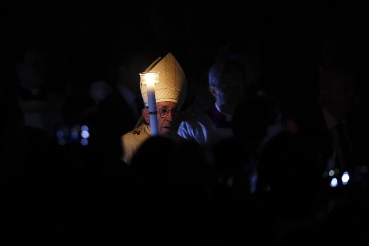 Pope Francis holds a candle as he presides over a solemn Easter vigil ceremony in St.