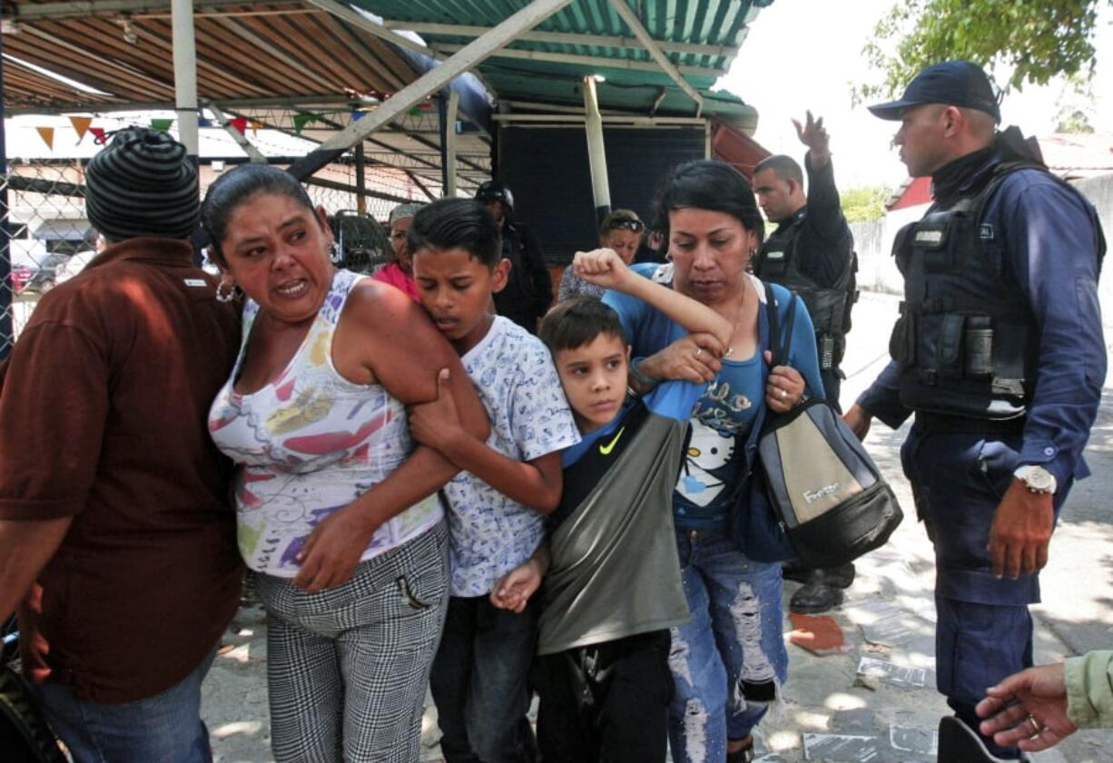 Police officers disperse the relatives of prisoners who were waiting to hear news about their family members imprisoned at a police station when a riot broke out, in Valencia, Venezuela, Wednesday, March 28, 2018. In a state police station housing more than one hundred prisoners, a riot culminated in a fire, requiring authorities to open a hole in a wall to rescue the inmates.