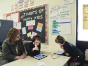 Felida Elementary School special education teacher Deb Lobdell, left, helps second-grader Carsten Edwards, 8, and first-grader, Scott Traux, 6, while they solve puzzles and design backgrounds on Code.org during their special education class March 29 at Felida Elementary School.